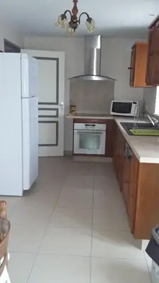 a kitchen with a white refrigerator and a white tile floor at La Nappie in Réalmont