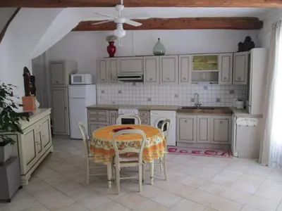 a kitchen with a table and chairs in a room at La Maison des Vendangeurs à Puisserguier in Puisserguier