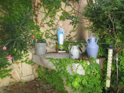 a statue of a woman sitting on a ledge with vases at La Maison des Vendangeurs à Puisserguier in Puisserguier