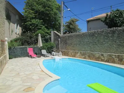 a swimming pool in a yard with a stone wall at La Maison des Vendangeurs à Puisserguier in Puisserguier