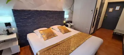 a bedroom with a large bed with gold pillows at Hôtel Renaissance in Castres