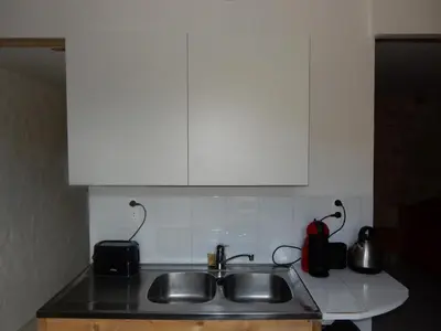 a kitchen counter with a sink and white cabinets at Cafe Vals in Vals