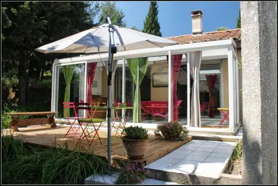 a conservatory with an umbrella on a wooden deck at Gîte du Fenouil in Lézignan-Corbières