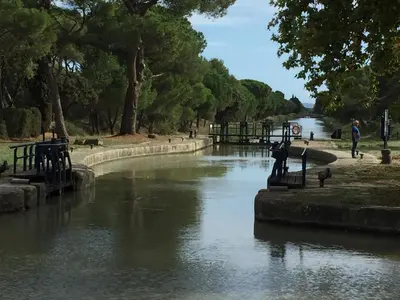 a river in a park with people walking on the banks at Gîte du Fenouil in Lézignan-Corbières