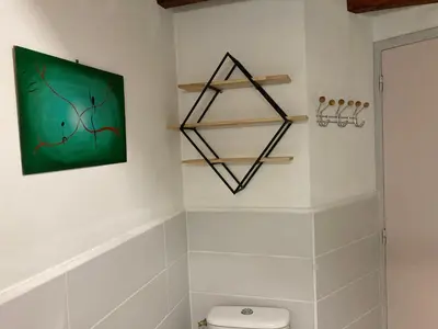 a bathroom with a green painting above a toilet at Gîte du Fenouil in Lézignan-Corbières