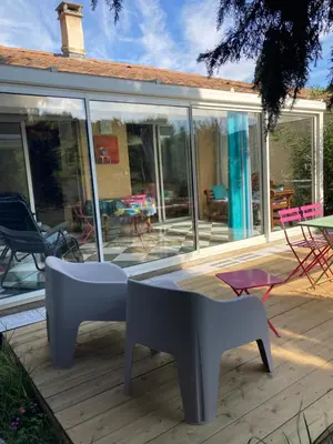 a screened porch with chairs and tables on a deck at Gîte du Fenouil in Lézignan-Corbières
