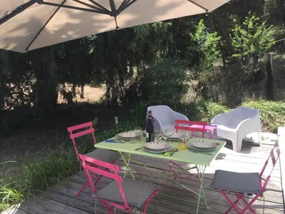 a table with four chairs and an umbrella at Gîte du Fenouil in Lézignan-Corbières