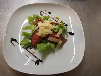 a white plate with a salad on a table at Hotel Axat in Axat
