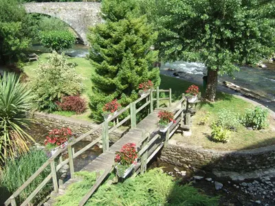 a wooden bridge with flowers on it next to a river at Hotel Axat in Axat