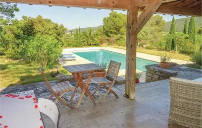 a table and chairs on a patio next to a swimming pool at Amazing Home In Ribaute in Ribaute