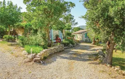 a driveway with a stone wall and trees in front of a house at Amazing Home In Ribaute in Ribaute