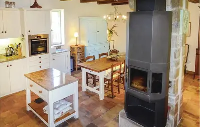 a kitchen with a fireplace in the middle of a room at Amazing Home In Ribaute in Ribaute