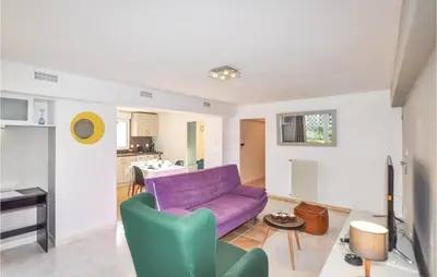 a living room with a purple couch and a kitchen at Cozy Apartment In Vinassan With Wifi in Vinassan