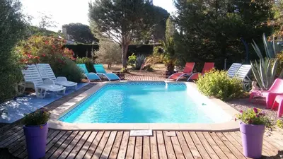 a swimming pool on a wooden deck with chairs around it at La Lucques Masabelle in Mirepeisset