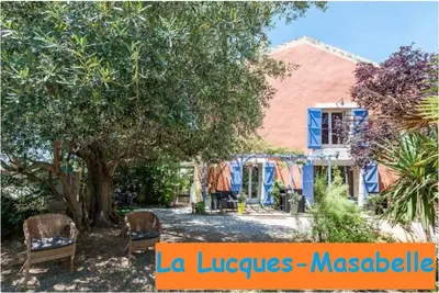a house with a tree and chairs in front of it at La Lucques Masabelle in Mirepeisset