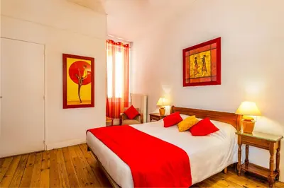 a bedroom with a large bed with red and yellow pillows at Logis Hôtel Restaurant des Corbières in Lagrasse