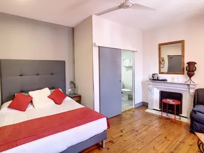 a bedroom with a bed with red pillows and a fireplace at Logis Hôtel Restaurant des Corbières in Lagrasse