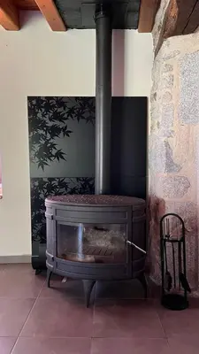 a stone fireplace in a room with a chair at gite a la campagne in Noailhac