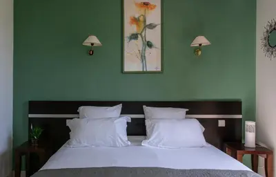 a bedroom with a bed with white pillows and green walls at Le Mas De Gaujac in Lézignan-Corbières
