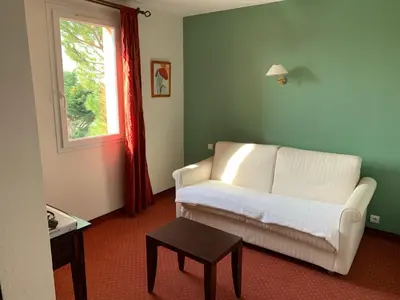 a living room with a white couch and a window at Le Mas De Gaujac in Lézignan-Corbières