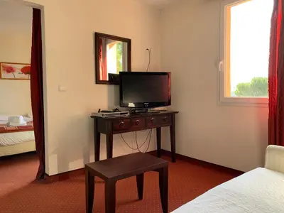 a room with a television on a table with a stool at Le Mas De Gaujac in Lézignan-Corbières