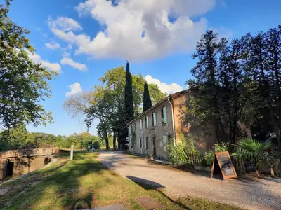 an old building with a sign on the side of a road at La Bonne Planque - Maison éclusière de La Planque in Mas-Saintes-Puelles