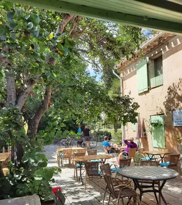 an outdoor patio with tables and chairs and trees at La Bonne Planque - Maison éclusière de La Planque in Mas-Saintes-Puelles