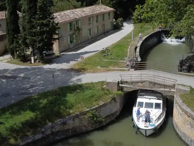a small boat is docked in a canal at La Bonne Planque - Maison éclusière de La Planque in Mas-Saintes-Puelles