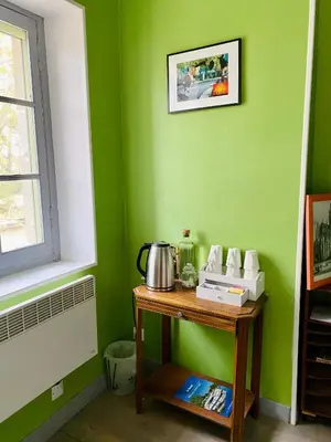 a table in a room with a green wall at La Bonne Planque - Maison éclusière de La Planque in Mas-Saintes-Puelles