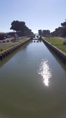 a canal of water with the sun reflecting in it at Appartement Le Flamant Rose in Port-la-Nouvelle