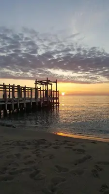 a pier on the water with the sun setting at Appartement Le Flamant Rose in Port-la-Nouvelle