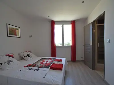 a bedroom with a bed and a window with red curtains at Peaceful Poolside Escape in Montouliers
