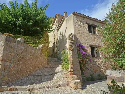 an alleyway leading to a stone building with flowers at Peaceful Poolside Escape in Montouliers
