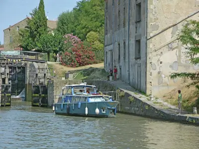 a blue boat in the water next to a building at Peaceful Poolside Escape in Montouliers