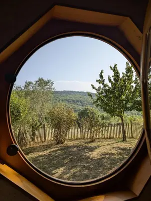 a round window with a view of a yard at Fount de Cousteno in Limbrassac