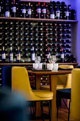 a table with two yellow chairs and wine bottles at LOGIS Hôtel Restaurant Le Clos Fleuri in Castelnaudary