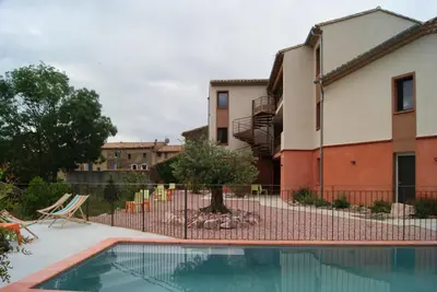 a swimming pool with a fence next to a building at Contact Hôtel Le Minervois - Hôtel & Restaurant Au nord de Carcassonne in Caunes-Minervois