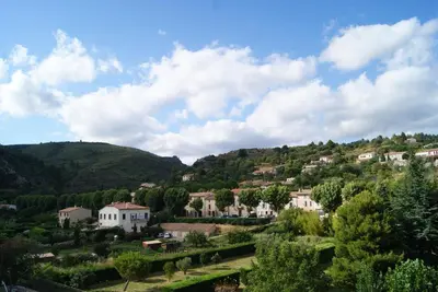 a village on a hill with houses and trees at Contact Hôtel Le Minervois - Hôtel & Restaurant Au nord de Carcassonne in Caunes-Minervois