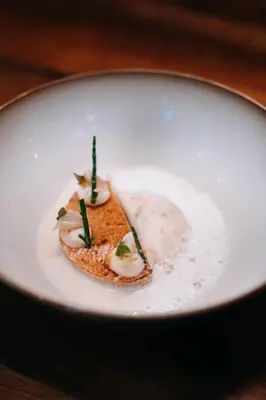 a piece of food on a white plate on a table at Domaine Riberach - Restaurant étoilé - Spa - Piscine naturelle - Vignoble bio in Bélesta