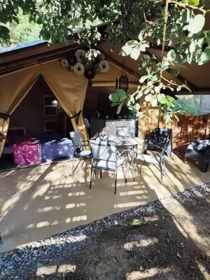 a tent with a table and chairs under a tree at Camping des vignes in Dun