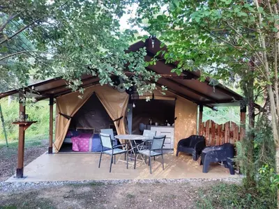 a tent with a table and chairs under a tree at Camping des vignes in Dun