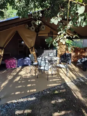 a tent with a table and chairs under a tree at Camping des vignes in Dun