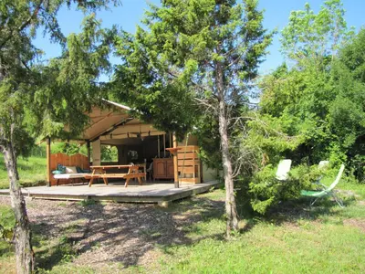 a cabin in the woods with a picnic table and trees at Camping des vignes in Dun