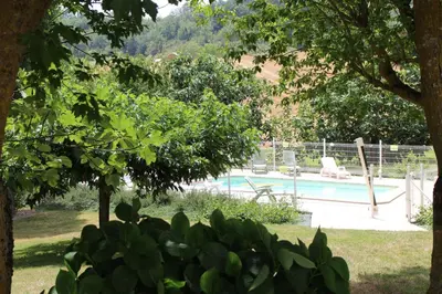 a swimming pool in a yard with chairs and trees at La Maison du Soleil in Saint-Gaudéric