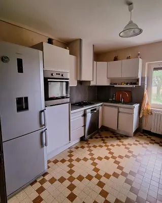 a kitchen with white appliances and a tile floor at La Maison du Soleil in Saint-Gaudéric