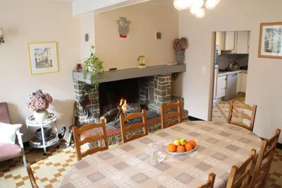 a dining room with a table and a fireplace at La Maison du Soleil in Saint-Gaudéric