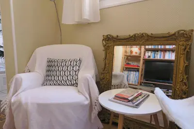 a living room with a chair and a mirror at B&B Le Patio En Ville - Chambres d'hôtes in Narbonne
