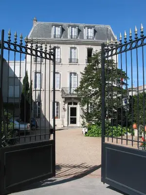 a gate in front of a white house at Hotel Montsegur in Carcassonne