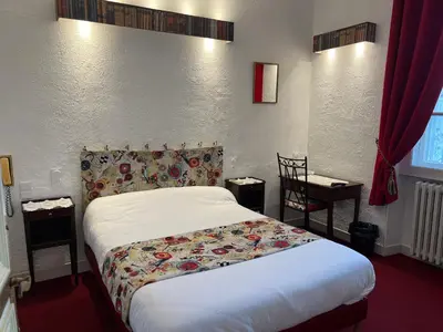 a bedroom with a bed and a table and a chair at Hotel Montsegur in Carcassonne