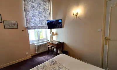 a bedroom with a bed and a desk with a television at Hotel Montsegur in Carcassonne